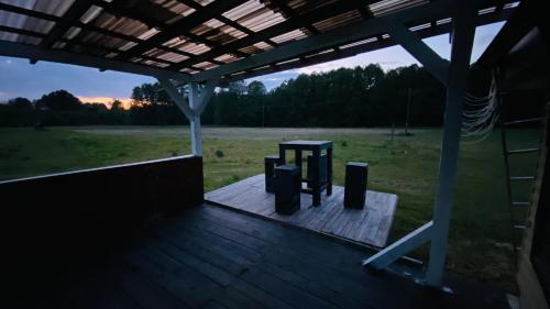 a wooden deck with a picnic table on a field at Domek Nad Stawem in Miedzichowo
