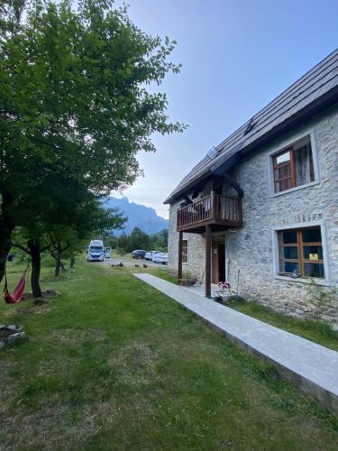 a stone house with a balcony and a yard at Rupa Guest House in Theth