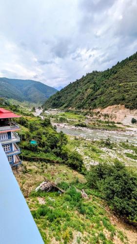 a view of a river with a building next to a mountain at Tara devi homestay in Dirang Dzong