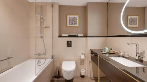 a bathroom with a tub and a toilet and a sink at Hilton Munich City in Munich