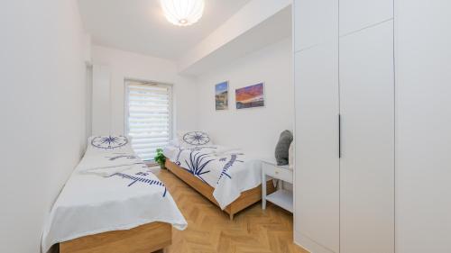 a white bedroom with two beds and a window at Sand Dunes, Sun & Snow in Dziwnów