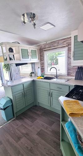 a kitchen with green cabinets and a sink at ML23 8 BERTH CARAVAN GOLDEN PALM CHAPEL ST LEONARDS in Chapel Saint Leonards