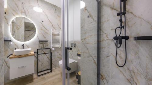 a bathroom with a shower with a sink and a mirror at Sand Dunes, Sun & Snow in Dziwnów