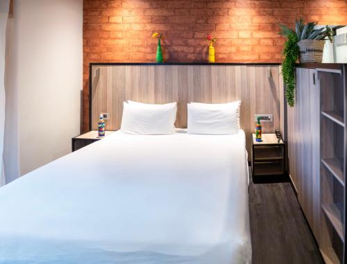 a bedroom with a white bed and a wooden wall at ONOMO Hotel Durban in Durban