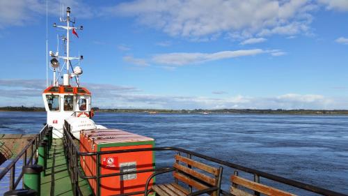 an orange and white boat on the water at Hostal Vista al Mar hct in Ancud