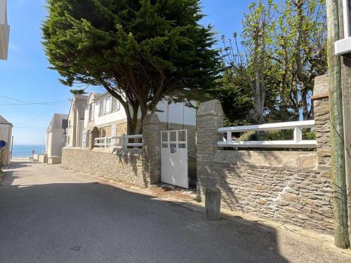 un mur de pierre avec une porte blanche et un arbre dans l'établissement Quiberon - Maison 5 pièces - Calme - 50m plage, jardin, animaux admis - FR-1-478-170, à Quiberon