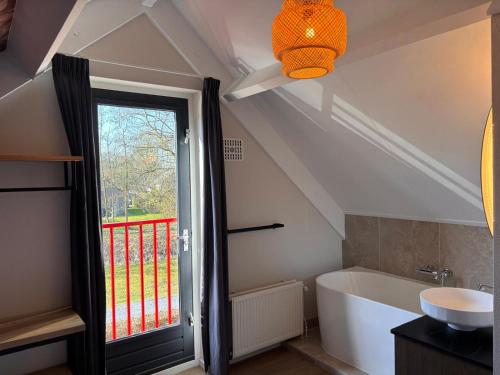 a bathroom with a bath tub and a window at Zeer comfortabel vakantiehuis op kleinschalig park 6 personen in Ewijk