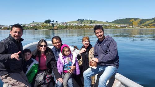 a group of people sitting in a boat on the water at Hostal Vista al Mar hct in Ancud