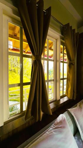 a window with a curtain in a bedroom at Saanidhya Sunset View Villa in Mukteswar