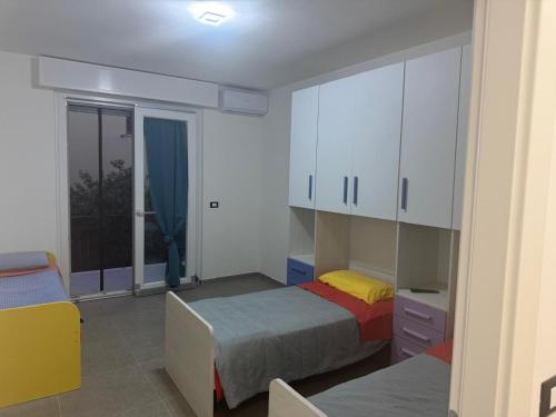 a bedroom with two beds and white cabinets and a window at Trilocale a pochi passi dal mare in Martinsicuro