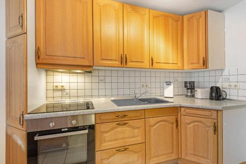 a kitchen with wooden cabinets and a sink at Ferienwohnung Sonnenblume in Rhadern