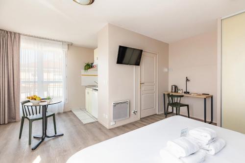 a room with a bed and a table with a desk at Appart'City Classic Lyon Villeurbanne in Villeurbanne