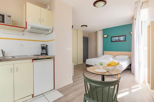 a kitchen and a room with a table and a bed at Appart'City Classic Lyon Villeurbanne in Villeurbanne