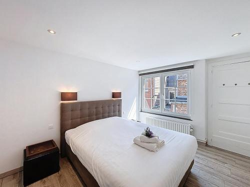 a bedroom with a large bed and a window at Maison 't Blyhuis in De Panne in De Panne