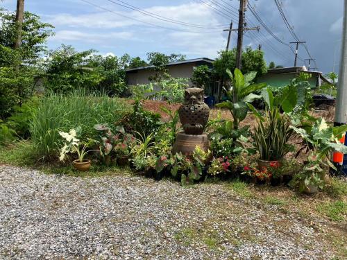 a garden with a statue in the middle of flowers at Rosemary Rayong in Ban Na