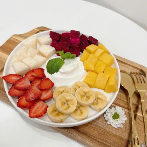 a plate of fruit and whipped cream and strawberries at Mập's Soul Hostel Đà Lạt in Da Lat