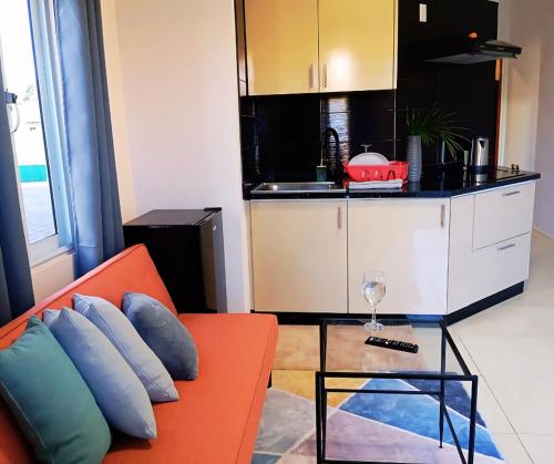 a living room with an orange couch and a kitchen at Dolfijn Studios in Paramaribo