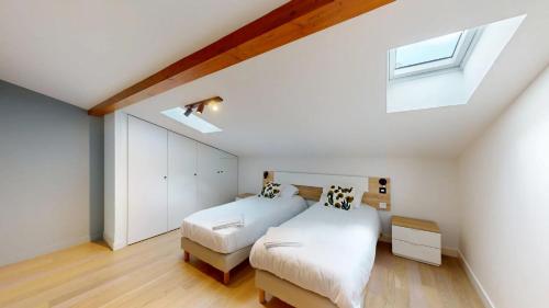 une chambre mansardée avec deux lits et une lucarne dans l'établissement Hyper centre T3 duplex-terrace, Esquirol, à Toulouse