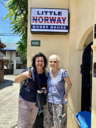 two women standing in front of a guest house at Little Norway Guesthouse - Mactan Cebu International Airport in Mactan