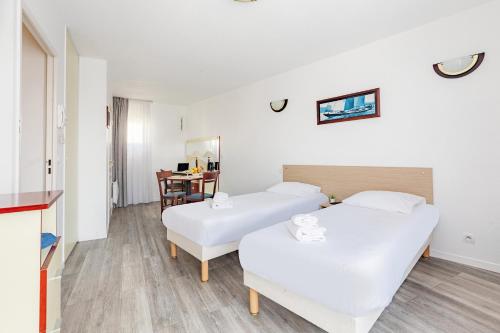 a hotel room with two beds and a table at Appart'City Classic Lyon Villeurbanne in Villeurbanne