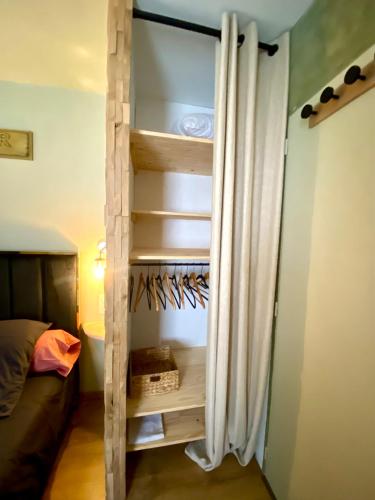 a closet in a room with a bed and a curtain at Maison romantique avec Balnéo Duo in La Bernerie-en-Retz
