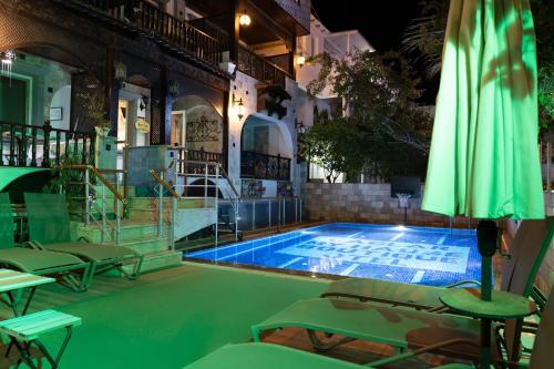 a swimming pool with green umbrellas and chairs at Çağlar my hause apart otel in Turgutreis