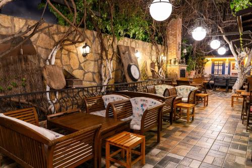 a restaurant with wooden tables and chairs and a stone wall at Çağlar my hause apart otel in Turgutreis