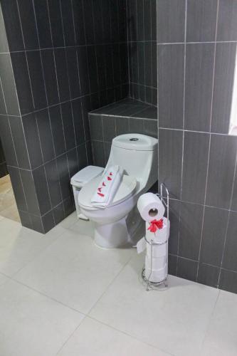 a bathroom with a toilet in a gray tiled wall at hotel plaza BRISAS MT in Punta Cana