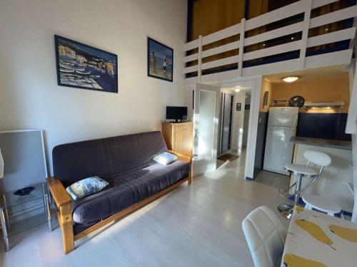 un salon avec un canapé noir et une cuisine dans l'établissement Studio Mezzanine 4 Pers, Plage à 50m, Parking Privé - FR-1-224C-591, à Saint-Jean-de-Monts
