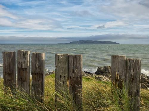 a row of wooden posts on a beach near the ocean at Stylish Dublin Coastal Home As Seen on TV in Donabate