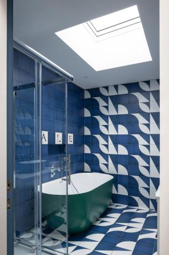 a bathroom with a green tub and blue tiles at Stylish Dublin Coastal Home As Seen on TV in Donabate