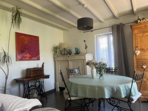 une salle à manger avec une table et un vase de fleurs. dans l'établissement La lumière bleue, à Tourville-sur-Arques