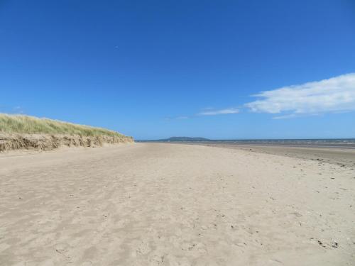 a beach with sand and a blue sky and clouds at Stylish Dublin Coastal Home As Seen on TV in Donabate
