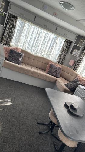 a living room with a large couch in front of a window at Happy Campers in Skegness