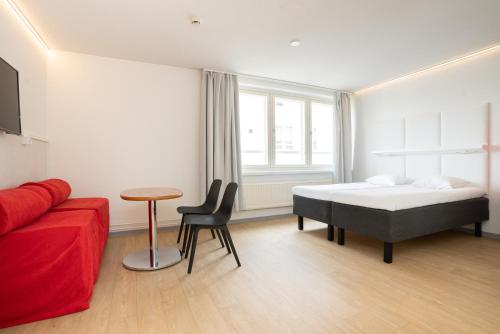 a bedroom with a bed and a red couch at Omena Hotel Jyväskylä in Jyväskylä