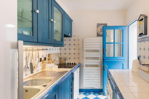 La salle de bains est pourvue de placards bleus et d'un lavabo. dans l'établissement Maison charme tout à pied coeur Pouliguen, au Pouliguen