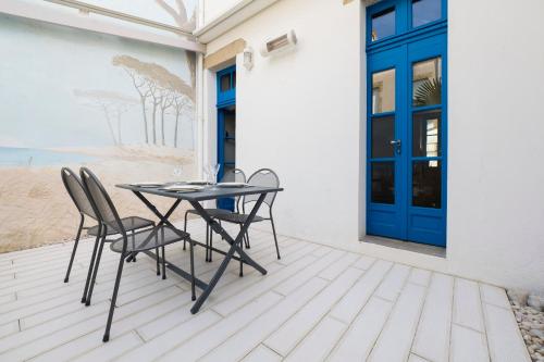 d'une terrasse avec une table et des chaises ainsi qu'une porte bleue. dans l'établissement Maison charme tout à pied coeur Pouliguen, au Pouliguen