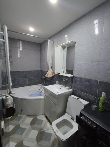 a bathroom with a toilet and a sink and a tub at A cozy corner in Saburtalo in Tbilisi City