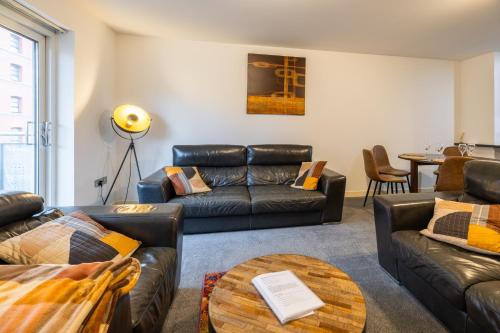 a living room with leather couches and a table at Waterfront Walk 3 Bedroom Apartment with Parking Pets and Workspace in Dundee