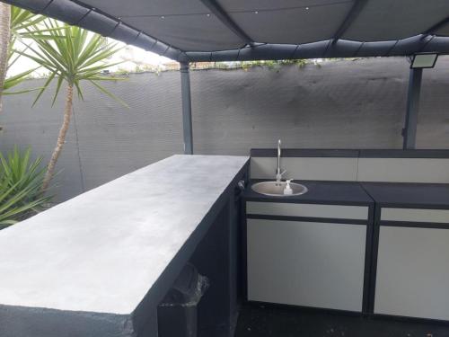 un comptoir en béton avec un évier sur une terrasse dans l'établissement Villa de standing avec piscine et climatisation, à Caissargues