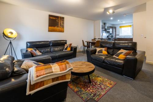 a living room with leather furniture and a table at Waterfront Walk 3 Bedroom Apartment with Parking Pets and Workspace in Dundee