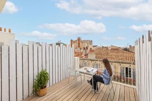 une femme assise à une table sur le balcon d'un bâtiment dans l'établissement The Babel Community Hôtel - Vieux Port, à Marseille
