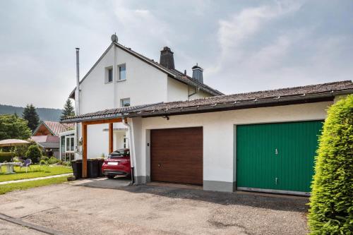 a white house with a green garage door at Fewo Cheny 2 mit 36qm in Titisee-Neustadt