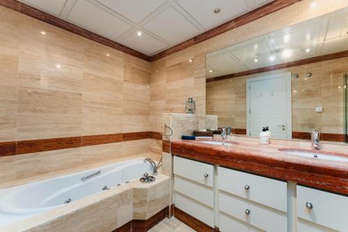a bathroom with a tub and two sinks and a mirror at Luxury Beachfront Penthouse Marbella - heated pool & seaviews in Estepona