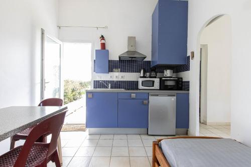 une cuisine avec des placards bleus et une table avec des chaises dans l'établissement U Turracconu, à Serra-di-Ferro