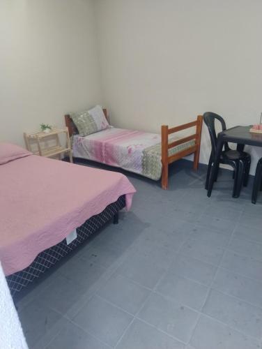 una habitación con dos camas y una mesa y una silla en Hostel cabo frio, en Cabo Frío