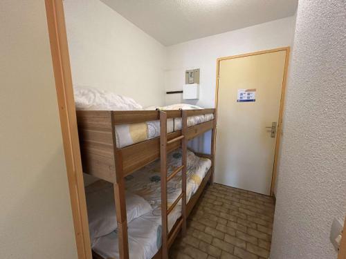 Cette chambre comprend 2 lits superposés et une porte. dans l'établissement Studio cabine 4 pers avec piscine, terrasse, proche commodités - Grau-du-Roi - FR-1-250-140, au Grau-du-Roi