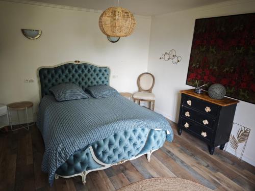 a bedroom with a blue bed and a dresser at Golf&Love in Normandy in Sainte-Opportune-du-Bosc