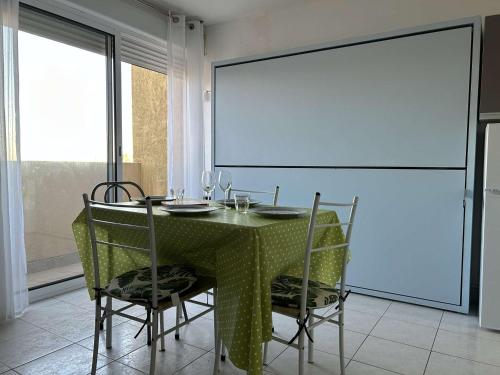 - une salle à manger avec une table, des chaises et un écran dans l'établissement Studio familial proche plage, 4 couchages - FR-1-229D-149, à Fleury