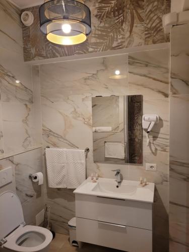 Un baño con lavabo, inodoro y espejo. en House Angelina, en Civitavecchia